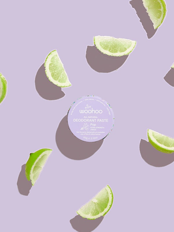 WooHoo Pop deodorant paste styled with fresh lime wedges on a purple background