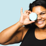 Smiling woman holding WooHoo Surf deodorant paste beside her face