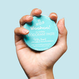 WooHoo Surf natural deodorant paste held in a hand against a blue background