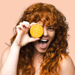 Smiling woman holding WooHoo Tango deodorant paste beside her face