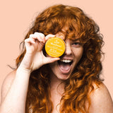 Smiling woman holding WooHoo Tango deodorant paste beside her face
