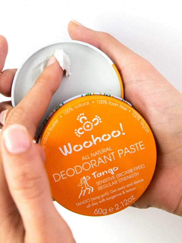 Hands holding an open tin of WooHoo Tango deodorant paste