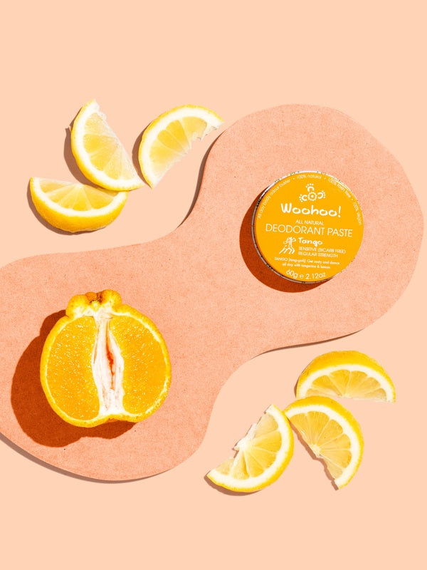 WooHoo Tango deodorant paste styled with fresh citrus on a peach background