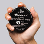 WooHoo Tux deodorant paste held in a hand against a grey background