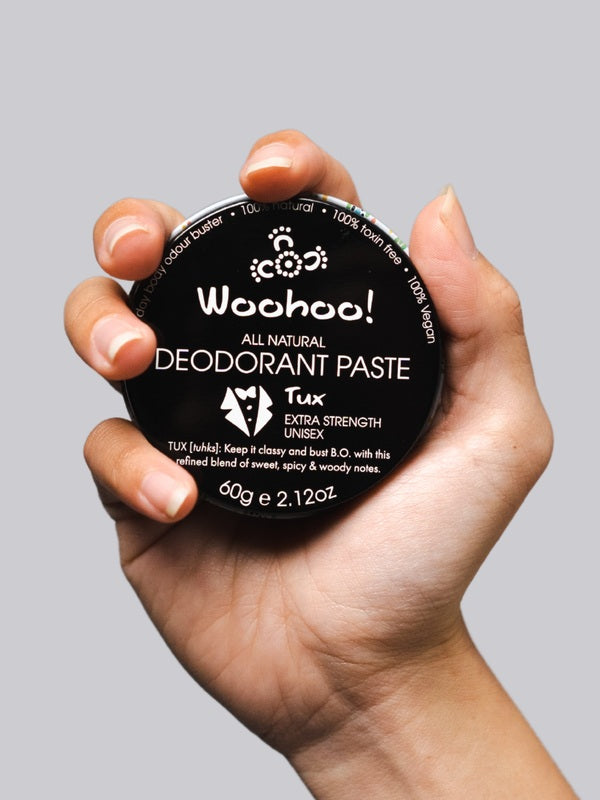 WooHoo Tux deodorant paste held in a hand against a grey background