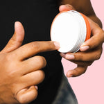 Hand scooping cream from an open tin of WooHoo Urban natural deodorant paste