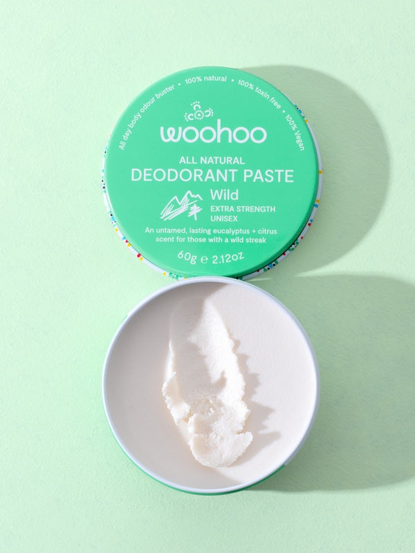 Open WooHoo Wild deodorant paste showing its creamy texture on a green background