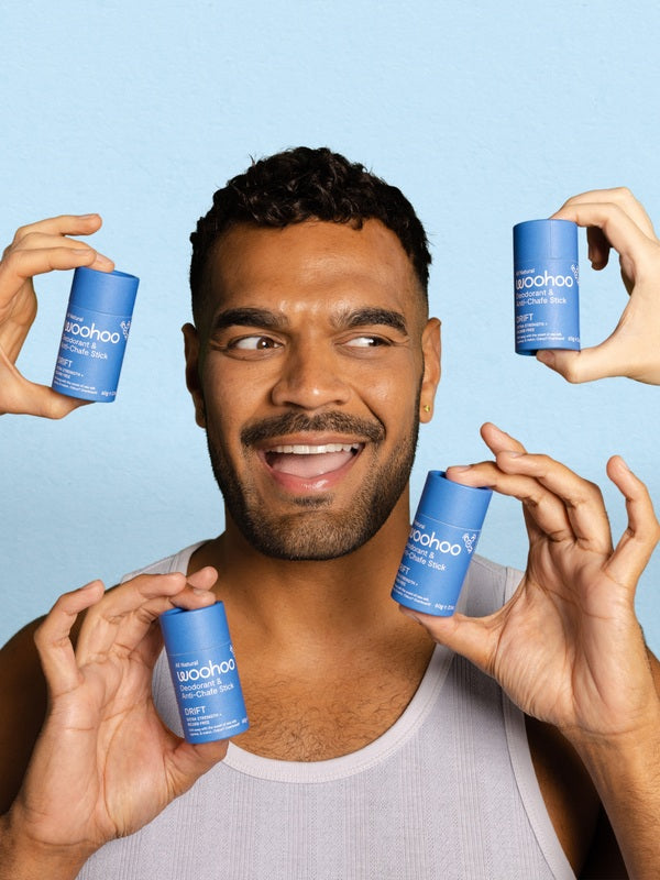 Smiling man surrounded by WooHoo Drift natural deodorant sticks