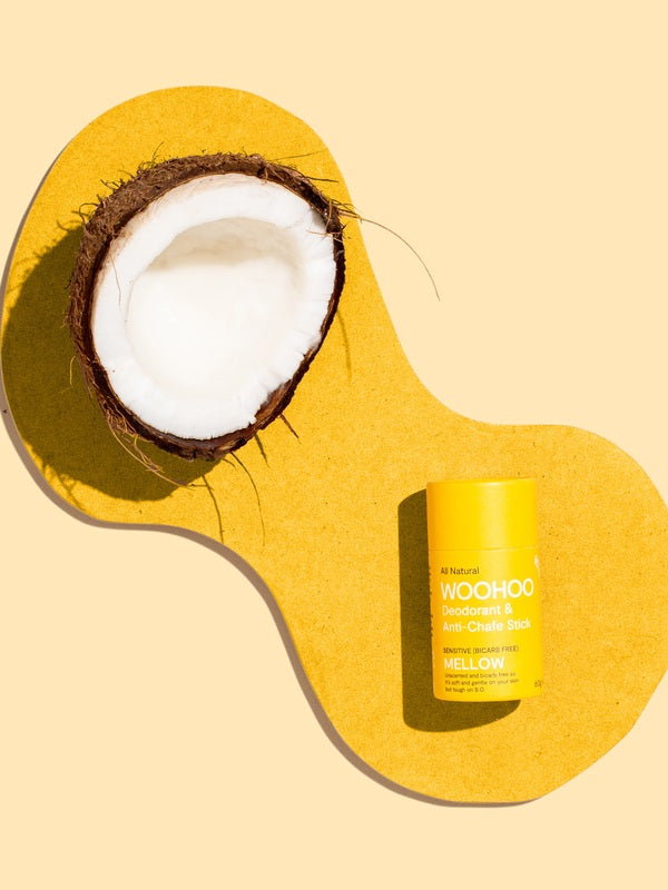 WooHoo Mellow deodorant stick styled with coconut on a yellow background