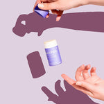 Hands opening a WooHoo Pop natural deodorant stick against a purple background