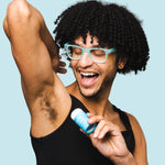 Smiling man applying WooHoo Surf natural deodorant stick to his underarm