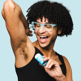 Smiling man applying WooHoo Surf natural deodorant stick to his underarm