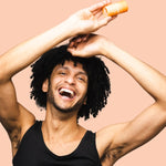 Smiling man applying WooHoo Tango deodorant stick to his underarm
