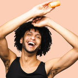 Smiling man applying WooHoo Tango deodorant stick to his underarm