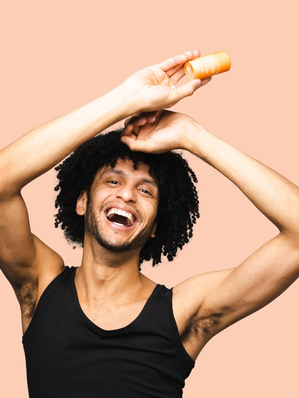 Smiling man applying WooHoo Tango deodorant stick to his underarm