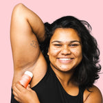 Smiling woman applying WooHoo Urban natural deodorant stick to her underarm