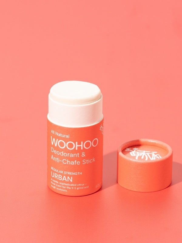 Open WooHoo Urban deodorant stick styled on a coral background
