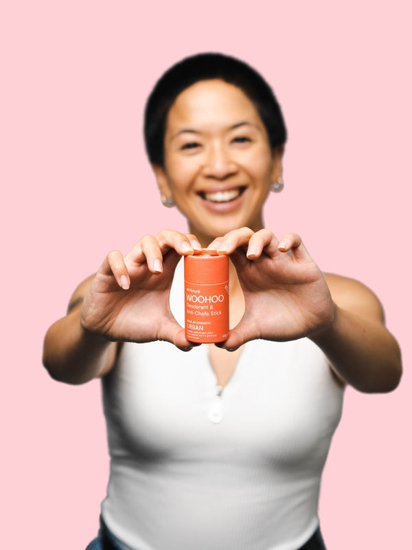 Woman holding WooHoo Urban natural deodorant stick toward the camera