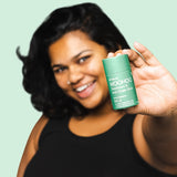 Woman holding WooHoo Wild natural deodorant stick toward the camera