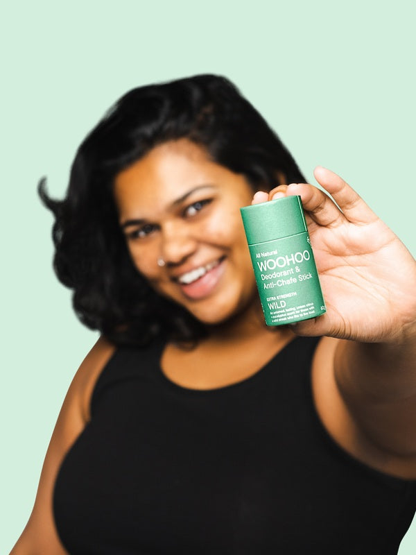 Woman holding WooHoo Wild natural deodorant stick toward the camera
