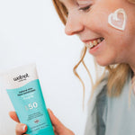 Woman applying Wotnot Natural Zinc Face Sunscreen SPF50 with CoQ10 to her cheek