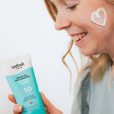 Woman applying Wotnot Natural Zinc Face Sunscreen SPF50 with CoQ10 to her cheek