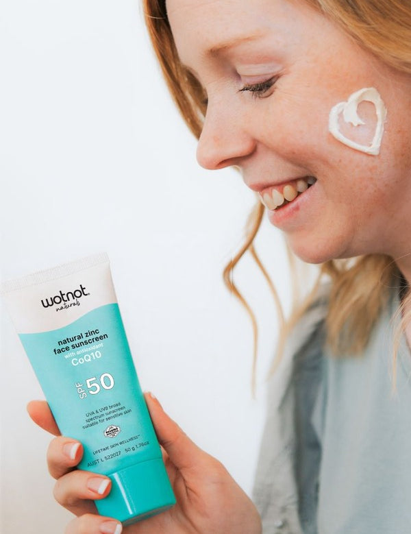 Woman applying Wotnot Natural Zinc Face Sunscreen SPF50 with CoQ10 to her cheek