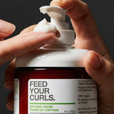 Hands dispensing Yarok Feed Your Curls Defining Crème