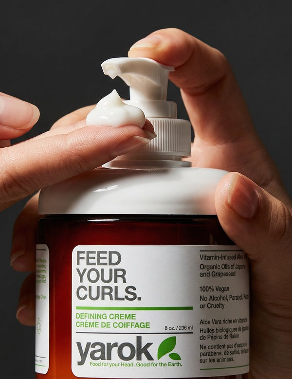 Hands dispensing Yarok Feed Your Curls Defining Crème