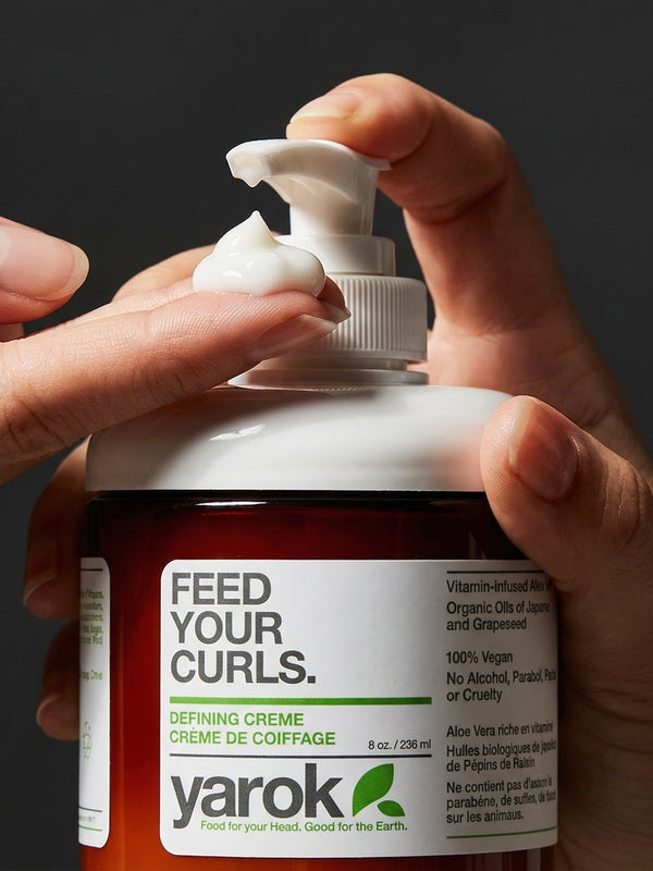 Hands dispensing Yarok Feed Your Curls Defining Crème