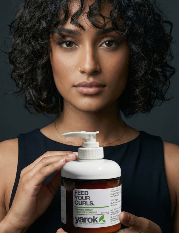 Woman with curly hair holding Yarok Feed Your Curls Defining Crème