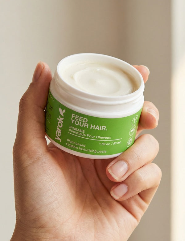 Hand holding an open jar of Yarok Feed Your Do Styling Pomade