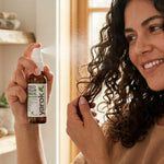 Woman applying Yarok Feed Your Ends Leave-In Conditioner to curly hair