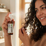 Woman applying Yarok Feed Your Ends Leave-In Conditioner to curly hair