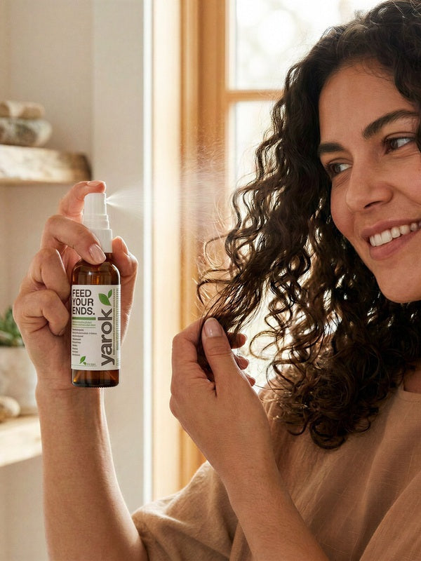 Woman applying Yarok Feed Your Ends Leave-In Conditioner to curly hair