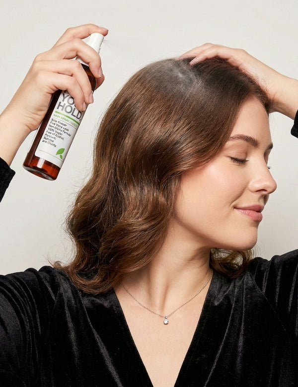 Woman spraying Yarok Feed Your Hold Hairspray onto styled hair