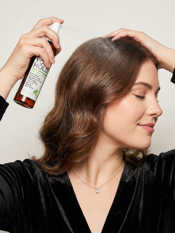 Woman spraying Yarok Feed Your Hold Hairspray onto styled hair