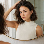 Woman massaging Yarok Feed Your Style Dry Shampoo into her roots in a mirror
