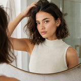 Woman massaging Yarok Feed Your Style Dry Shampoo into her roots in a mirror
