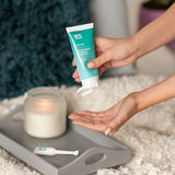 Hands dispensing YES WB Water-Based Lubricant beside a bed