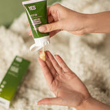 Hands dispensing YES OB Plant Oil-Based Lubricant beside a bed