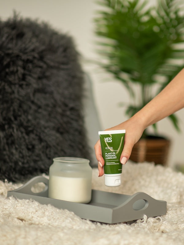 Hand picking up YES OB Plant Oil-Based Lubricant from a bedside tray