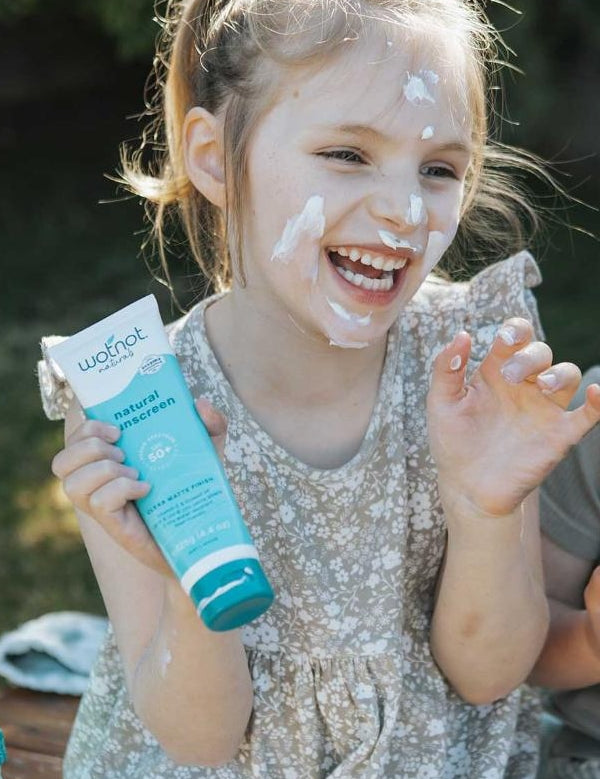 Child holding Wotnot Natural Sunscreen SPF 50 at the beach