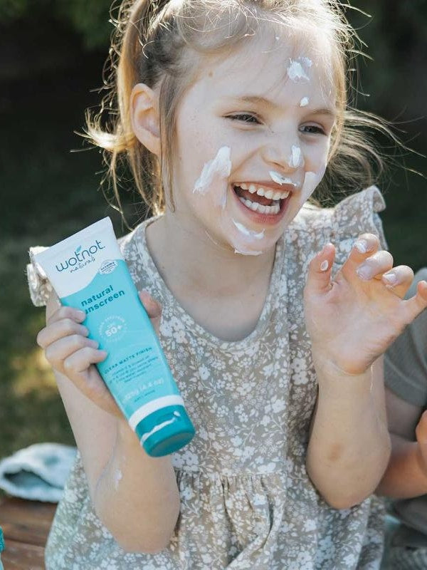 Child holding Wotnot Natural Sunscreen SPF 50 at the beach